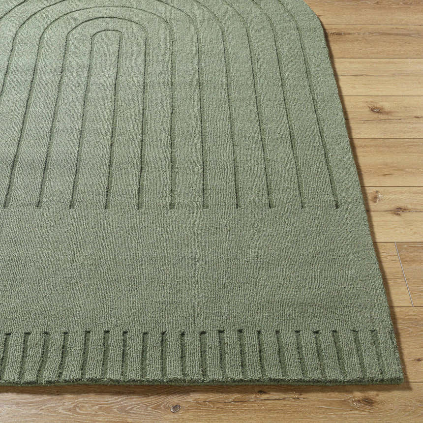 Close-up of the Arnona Green Area Rug showing its wool texture and contemporary arch design on a wood floor. Front