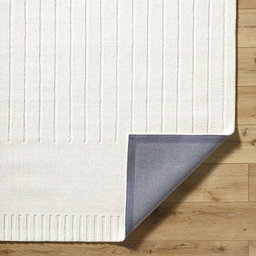 Close-up of the hand-loomed Arnona Off White Area Rug showing its ribbed texture and gray backing on a wood floor. Fold
