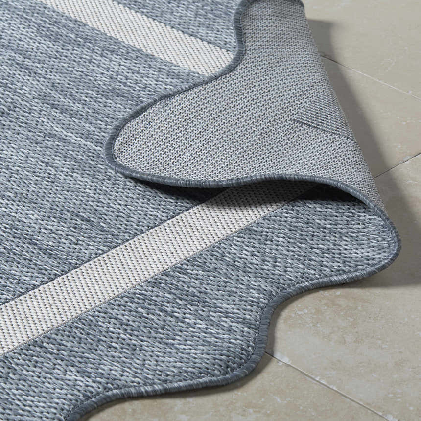 Close-up of the Varro Blue Area Rug showing its woven texture, cream stripes, and rounded edge. Fold