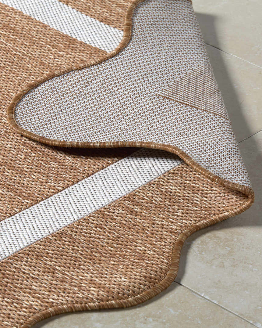 Close-up of the machine woven Varro Rust Area Rug showing cream stripes, rust color, and backing. Fold