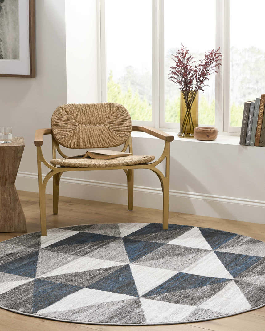 Cozy reading nook with a round Volant area rug in blue, gray, and white geometric pattern under a woven chair. Roomscene-Round