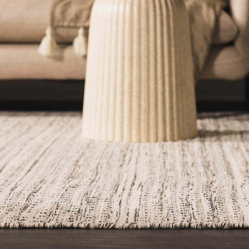 Close-up of the hand woven Williford Wool Area Rug in black and cream, showcasing its texture and striped design. Styleshot