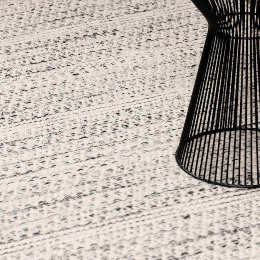 Close-up of the cream and black Williford Wool Area Rug, hand woven texture, with a black wire side table. Styleshot