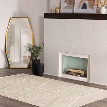 Living room scene with cream Woodew Modern Wool Rug, fireplace, gold mirror, and dark vases. Roomscene-Rectangle