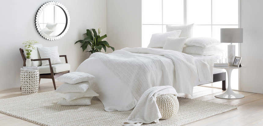 Bright bedroom scene with a cream Christoval Area Rug, white bedding, and natural accents. Roomscene-Rectangle