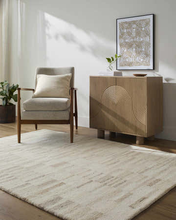Living room scene with ash and pearl Axelle Area Rug, gray chair, and wooden cabinet. Roomscene-Rectangle