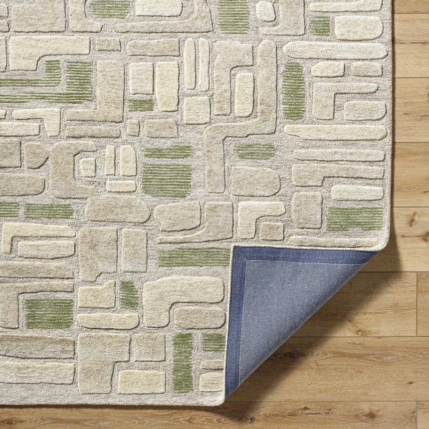 Close-up of the Alaqua Area Rug showing the geometric design in ash, desert sand, and slate blue on a wood floor. Fold