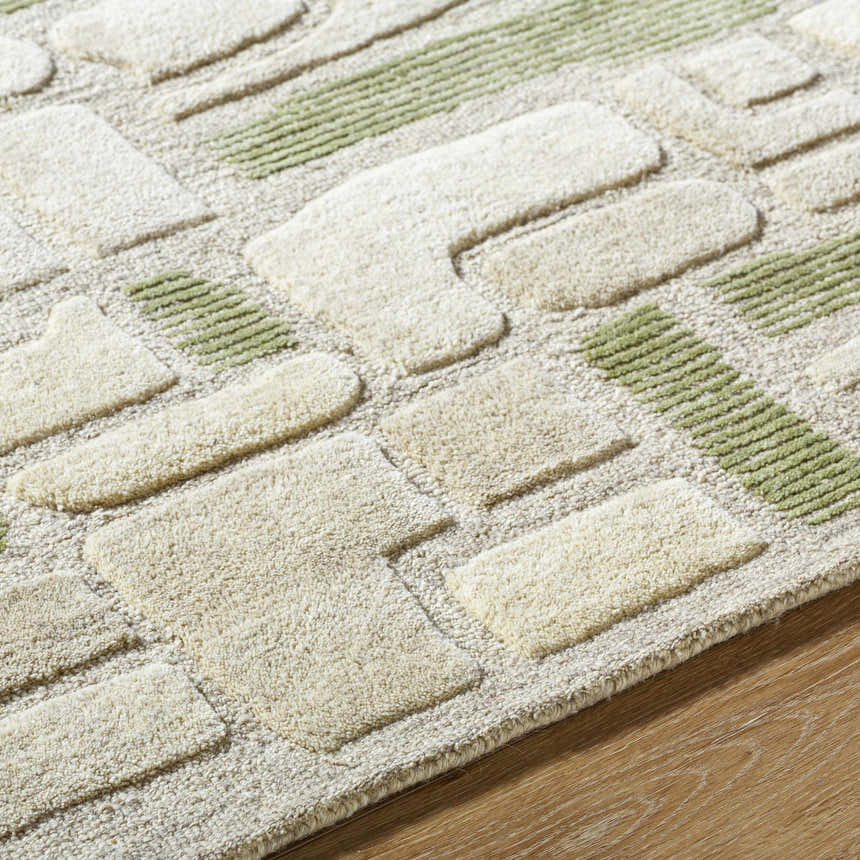 Close-up of the hand-tufted Alaqua Area Rug. Features a geometric design in ash, desert sand, and slate blue wool. Texture