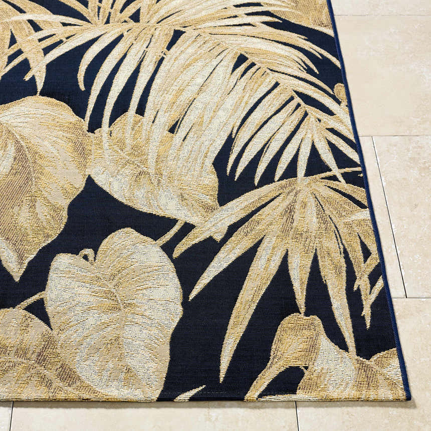 Close-up of the Amirah Midnight Blue area rug featuring a beige tropical leaf pattern on a dark blue background. Front