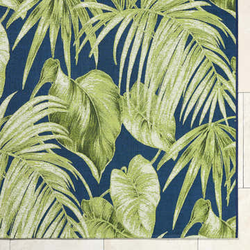Close-up of Amirah Teal Area Rug featuring a vibrant green tropical leaf pattern on a textured navy blue background. Corner