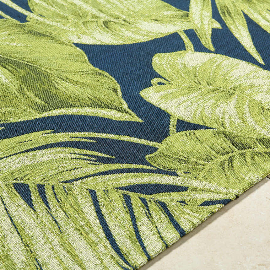 Close-up of the Amirah Teal Area Rug featuring a vibrant green leaf pattern on a deep teal background. Coastal style. Texture