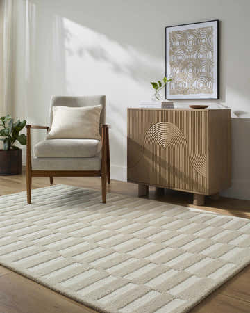 Living room scene with a beige and cream Uther Area Rug, gray chair, and modern wood cabinet. Roomscene-Rectangle