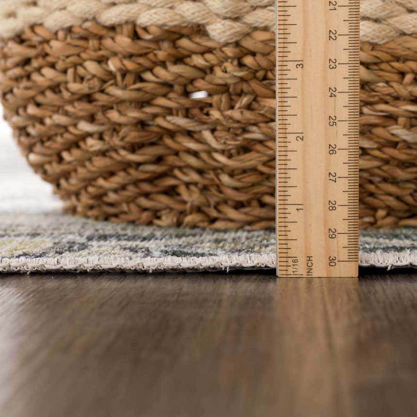 Close-up of Holi-4606 rug edge with ruler showing pile height, next to a woven basket. Black and gold farmhouse style. Pile