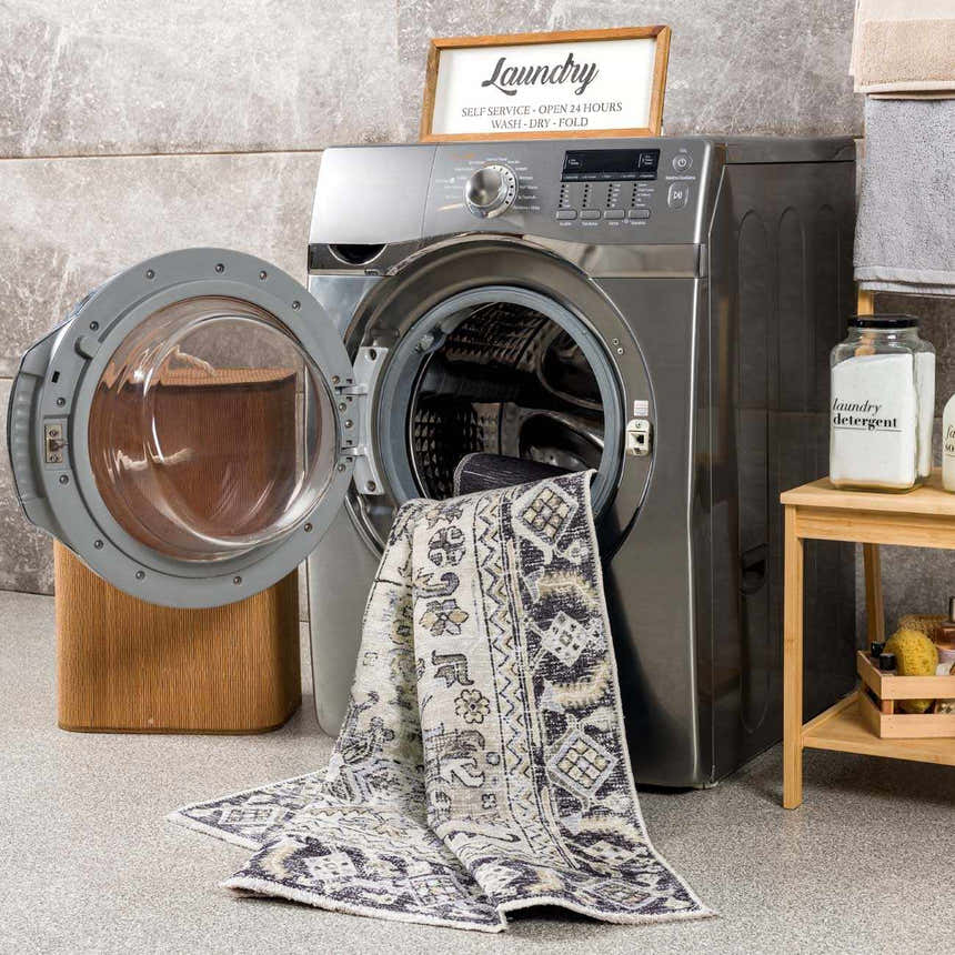 Laundry room scene with Holi-4606 black and gold washable rug partially in the washing machine. Farmhouse style. Washing-Machine