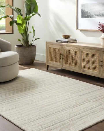 Living room scene with a light silver Yuuta Modern Wool Rug, beige chair, and wood cabinet. Roomscene-Rectangle