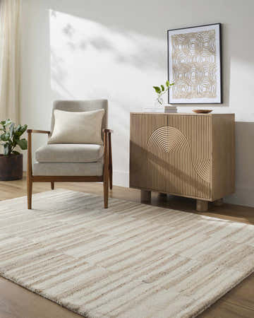 Living room scene with beige Yuuma Area Rug, light wood floors, gray chair, and modern cabinet. Roomscene-Rectangle
