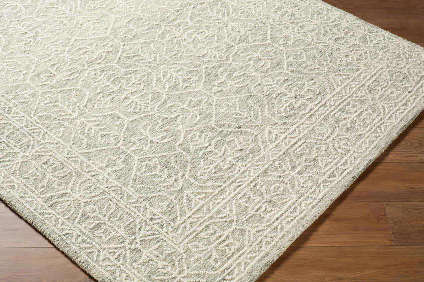 Close-up of the Yadid Gray Wool Area Rug showing its traditional off-white pattern and hand-tufted texture. Corner