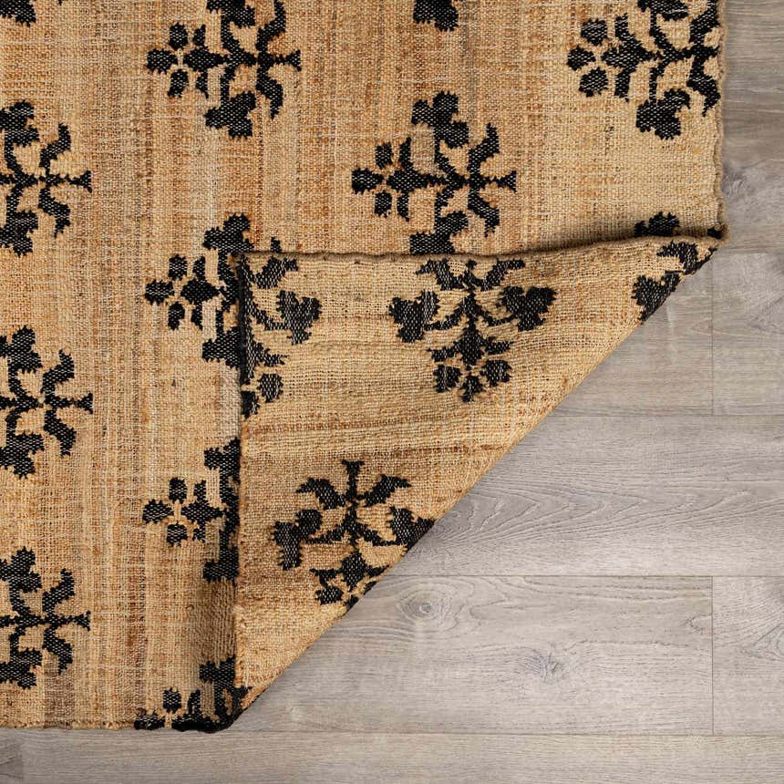 Close-up of the Albina Florentine Jute&Wool Rug showing black floral pattern on natural jute texture. Hand woven rug detail. Fold