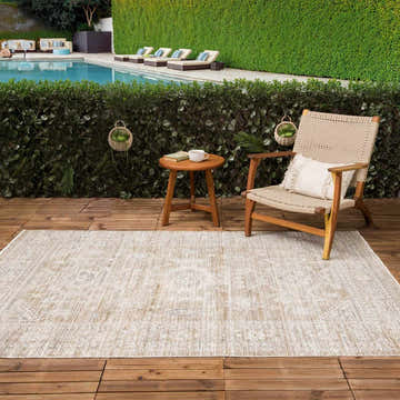 Outdoor patio scene with a Yamir Washable Outdoor Rug, chair, side table, and pool in the background. Roomscene-Rectangle