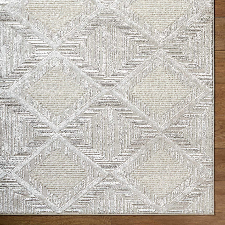 Close-up of the Yayoi Area Rug. Cream, ivory, and gray geometric diamond pattern with textured details. Corner