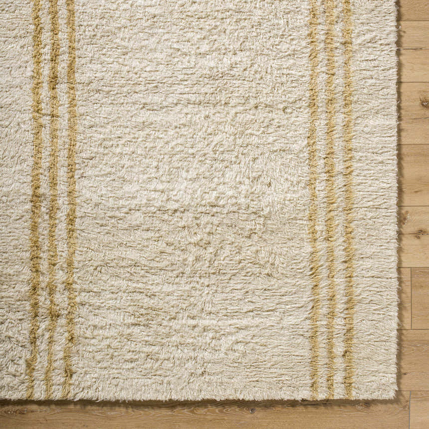 Close-up of the hand-tufted Yahto Area Rug. Camel and tan stripes on a pearl wool rug with a soft, shaggy texture. Corner