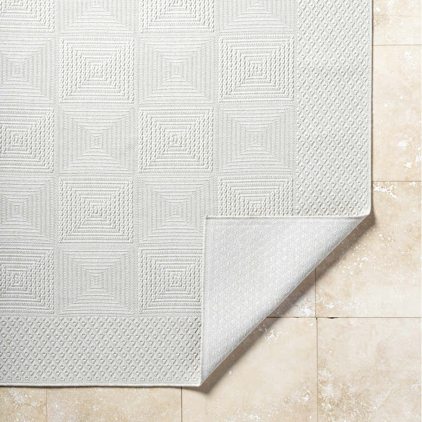 Close-up of the Anabia White Area Rug showing its geometric square pattern and textured weave on a neutral tile floor. Fold