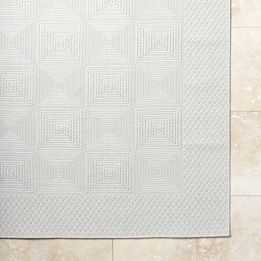 Close-up of the Anabia White Area Rug showing its light silver color and geometric square pattern. Corner