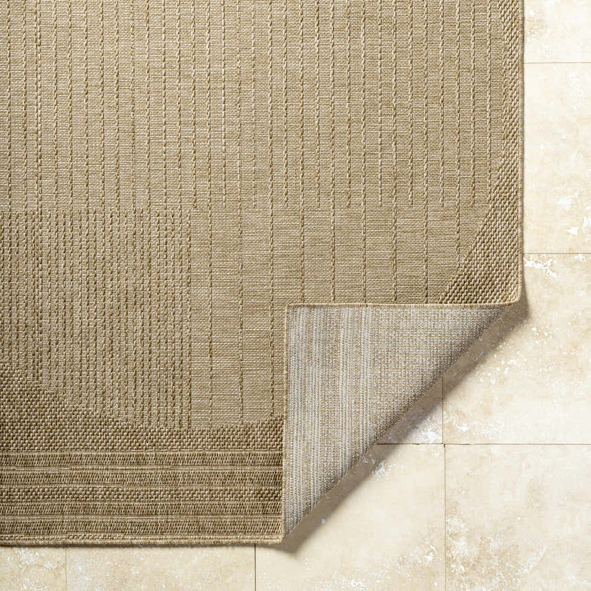 Close-up of the Yuley Brown Area Rug showing its woven texture, prairie dust and tan colors, and folded corner. Fold