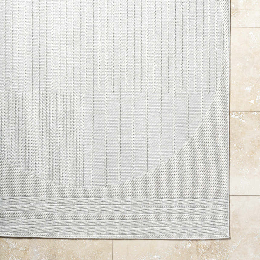 Close-up of the Yuley White Area Rug showing its light silver color, textured weave, and geometric border detail. Corner