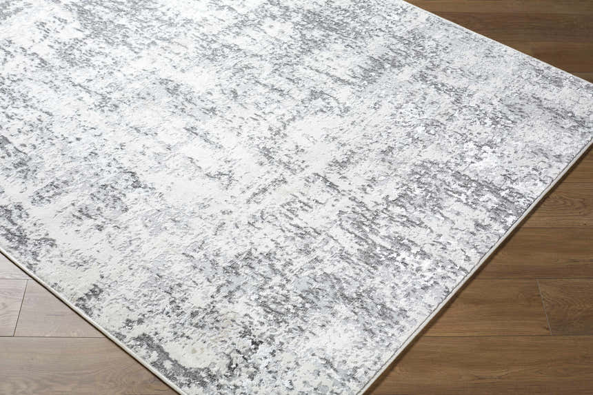 Close up of the Alviva Area Rug, a contemporary rug with charcoal, gray, and white abstract pattern. Corner