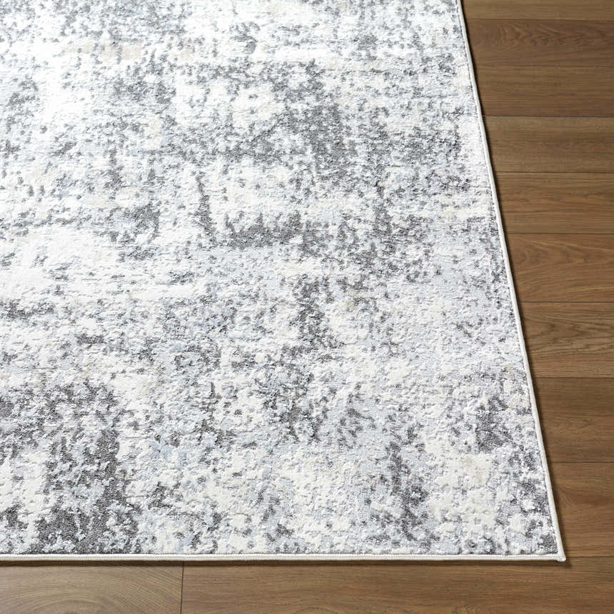 Close up of the Alviva Area Rug showing its charcoal, gray, and ivory abstract pattern and texture on wood flooring. Front
