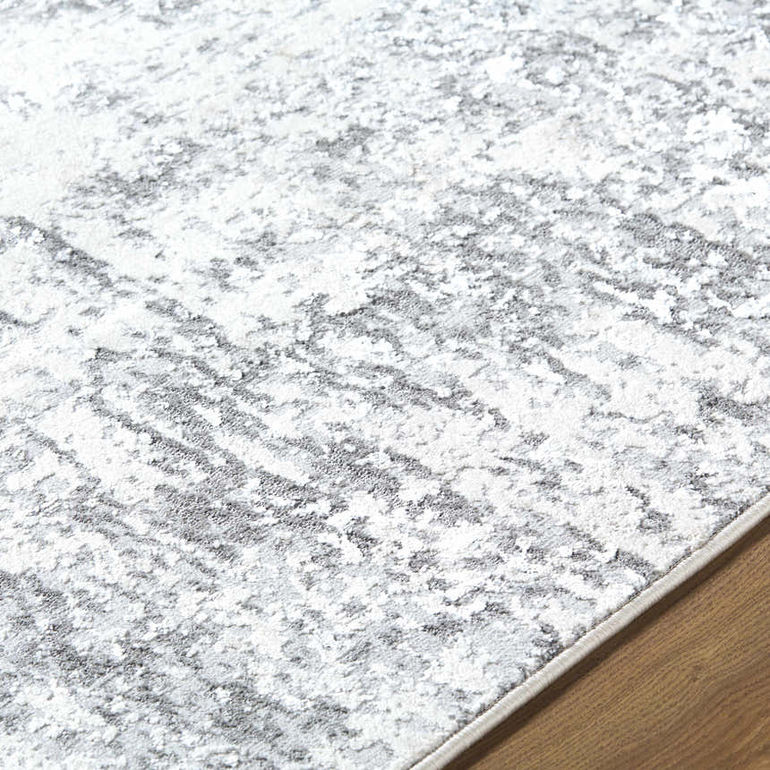 Close up of the Alviva Area Rug showing its charcoal, gray, and white contemporary pattern and soft texture. Texture