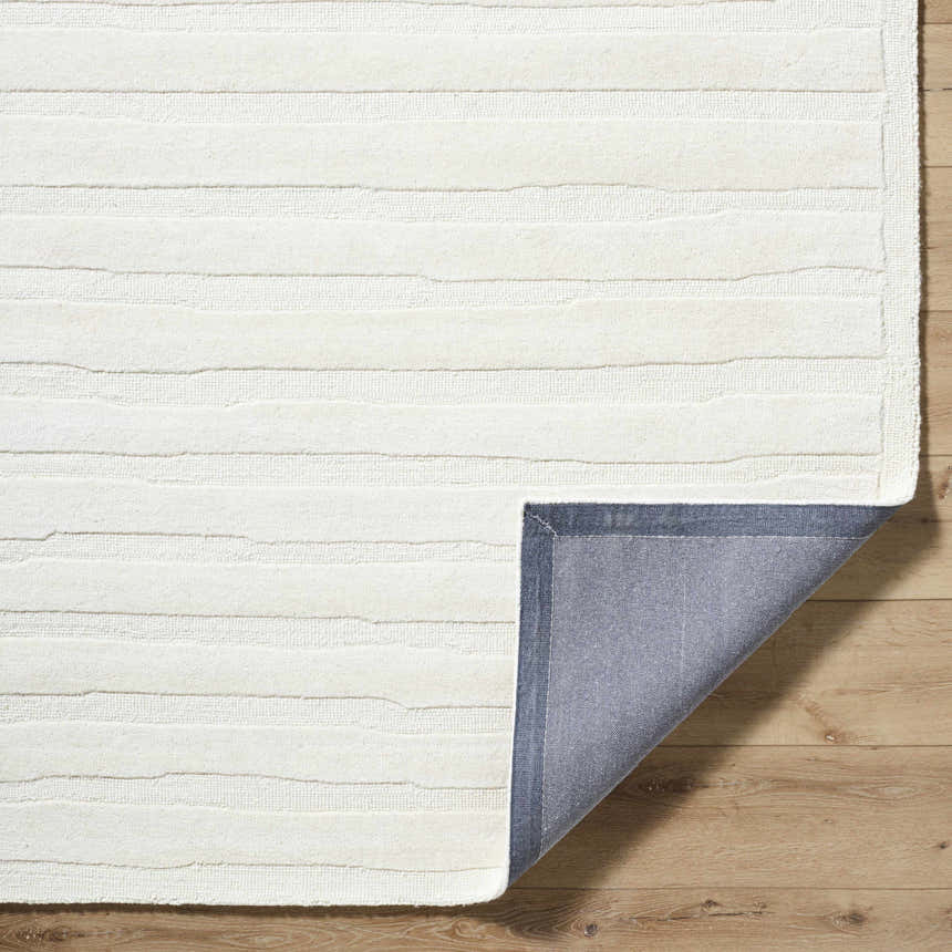 Close-up of the Zerah White Wool Area Rug showing the textured, horizontal line design and the rug's backing. Fold
