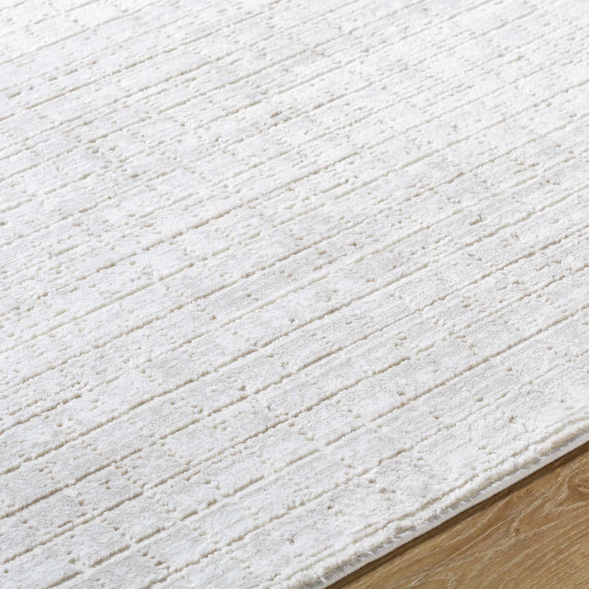 Close-up of the Arnulf 3D Textured Washable Rug. Cream and ivory polyester rug with a subtle, raised linear pattern. Texture