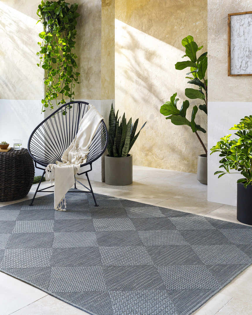 Contemporary patio scene with gray checkered Aulani Area Rug, modern chair, and potted plants. Roomscene-Rectangle