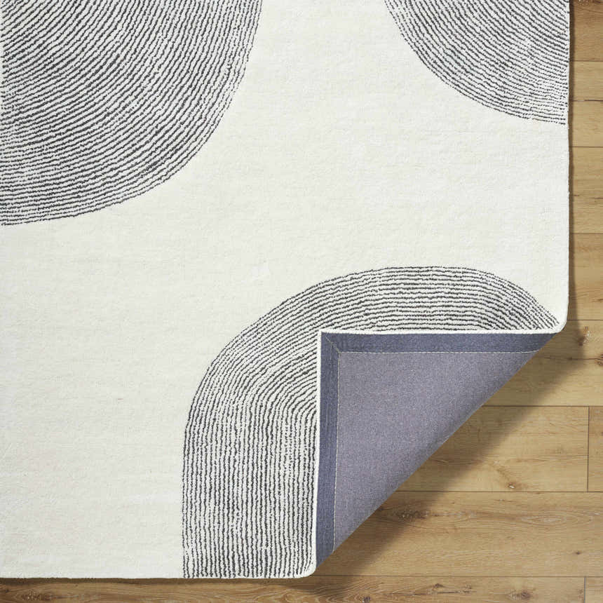 Close-up of the Zytka Area Rug showing the desert sand color and contemporary silver gray circle pattern. Hand-tufted wool texture. Fold