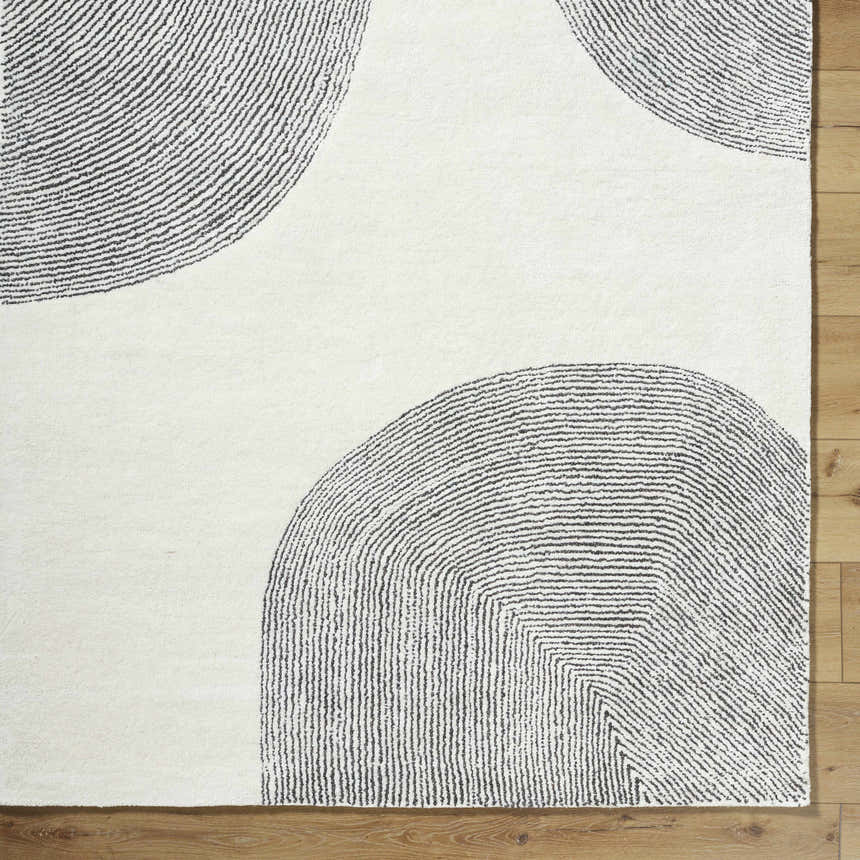 Close-up of Zytka Area Rug. Hand-tufted wool rug in desert sand with light silver and silver gray geometric circle design. Corner