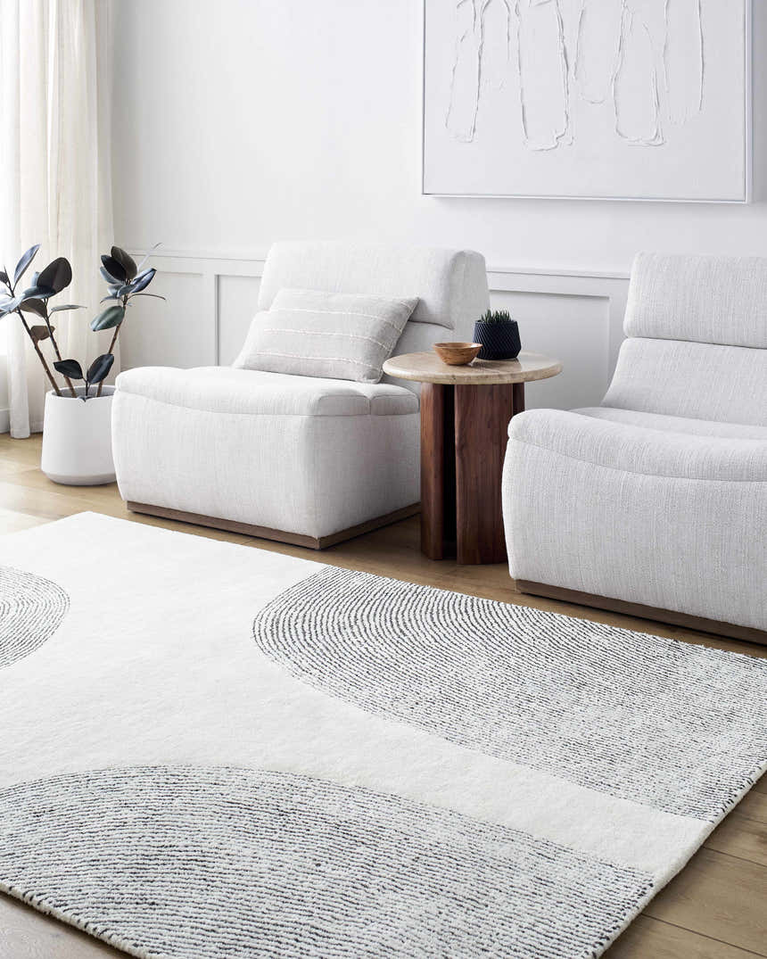 Living room scene with the Zytka Area Rug, featuring a desert sand and silver gray circular pattern. White armchairs and decor. Roomscene-Rectangle