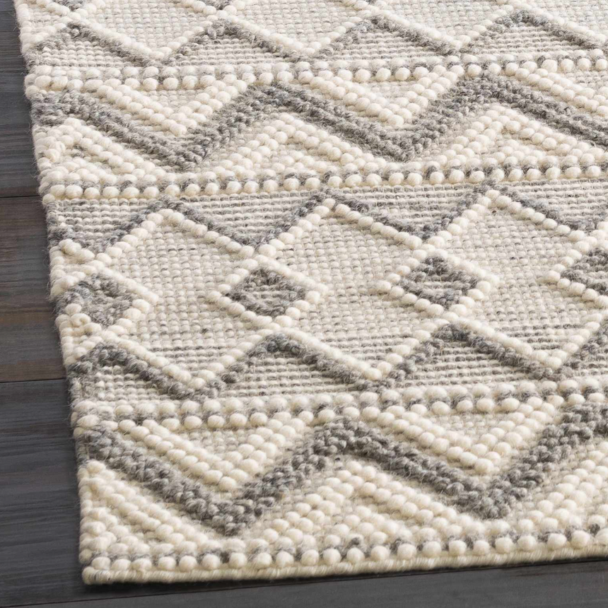 Close-up of the hand woven Whittington Gray&Cream Wool Rug, featuring a geometric diamond pattern and textured wool. Corner
