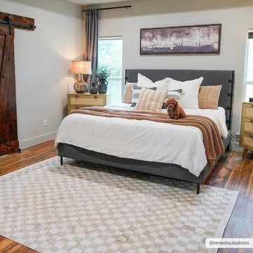 Bedroom scene with Benjy Irregular Checkboard Rug in cream and gold, gray bed, and wood accents. A cute dog sits on the bed. Roomscene-Rectangle