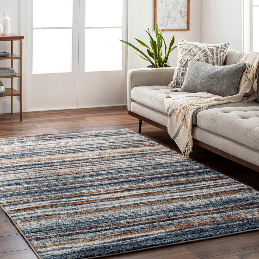 Living room scene with a blue, brown, and cream striped Dumaguil Thick Luxe Rug under a gray sofa. Roomscene-Rectangle