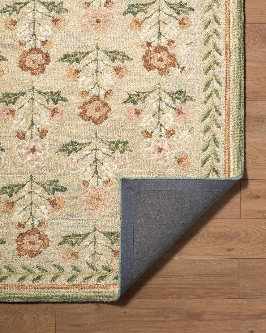 Close-up of the hand-tufted Acacia Area Rug. Features a floral pattern in cream, pink, brown, and green on a wood floor. Fold