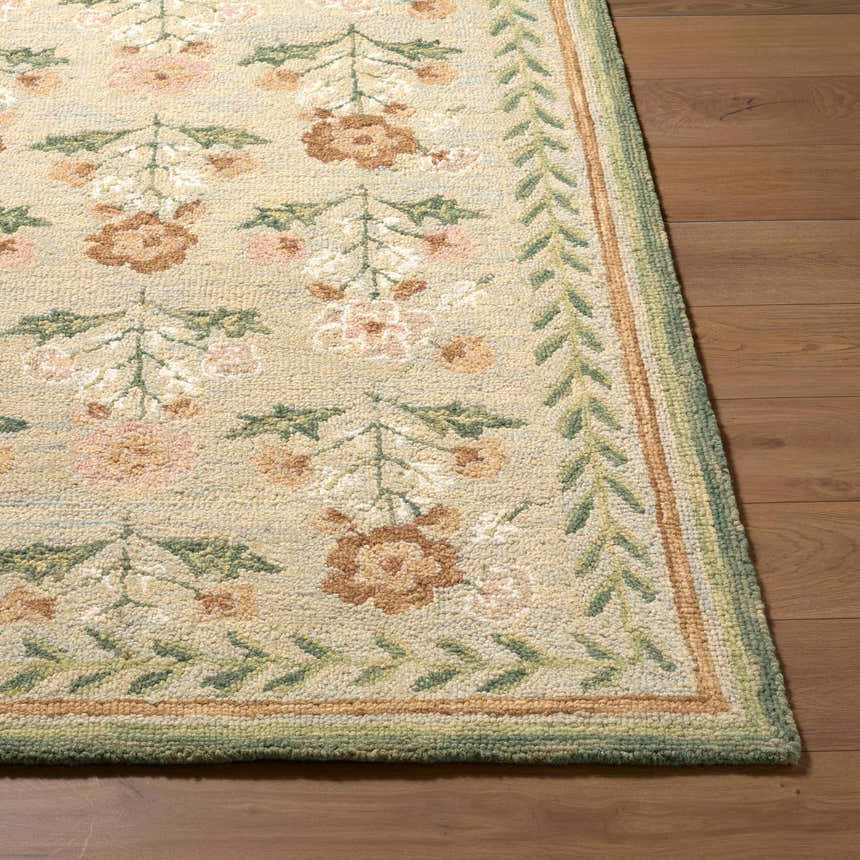 Close up of a hand-tufted Acacia Area Rug. Farmhouse style wool rug with floral pattern in beige, pink, and green on wood floor. Front