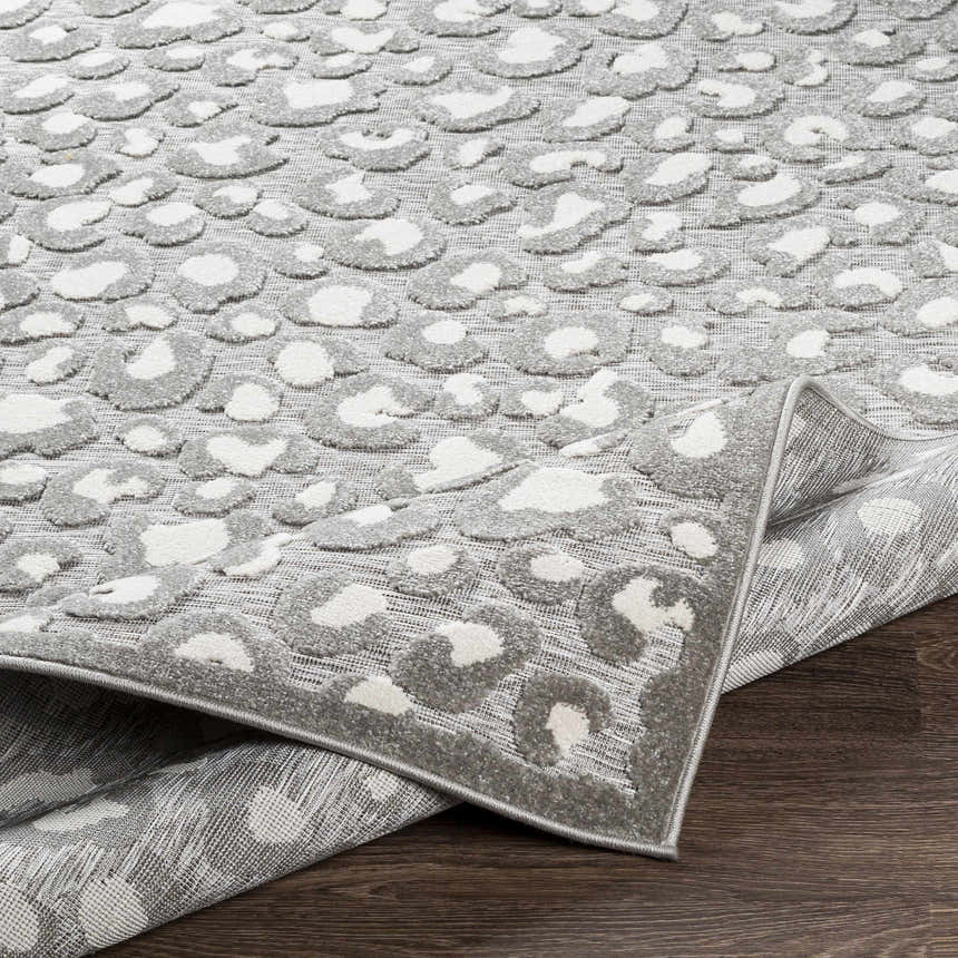 Close up of the Greensborough Performance Rug showing a gray and white animal print pattern and machine woven texture. Fold