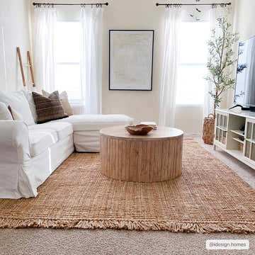 Living room with a light brown Senneterre Natural Jute Rug, white sofa, round wood coffee table, and neutral decor. Roomscene-Rectangle