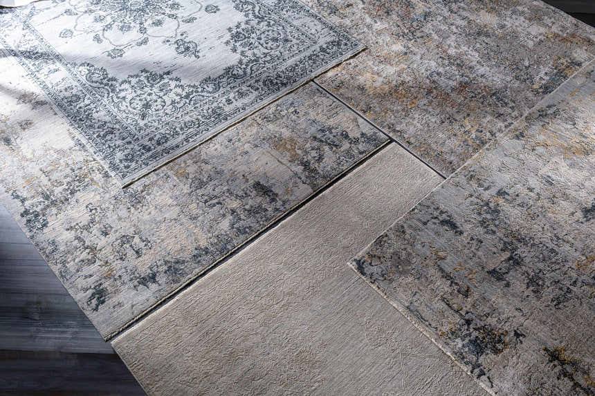 Close-up of Pinjarra Luxe Rug samples in charcoal, cream, and gray, showing contemporary designs and textures. Styleshot