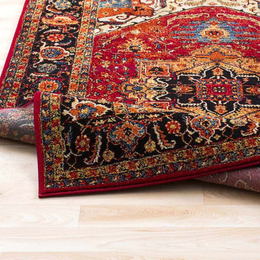 Close-up of the Malpas Area Rug showing its black, burgundy, and ivory traditional pattern and machine-woven texture. Fold