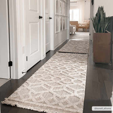 Hallway with a beige geometric Malilinao Area Rug runner on dark wood floors, white doors, and neutral decor. Roomscene-Runner