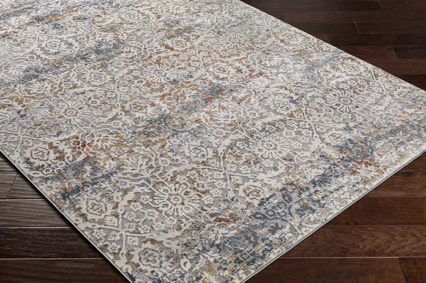 Close-up of the Marden Textured Luxe Area Rug showing brick red, camel, charcoal, and cream colors on a dark wood floor. Corner