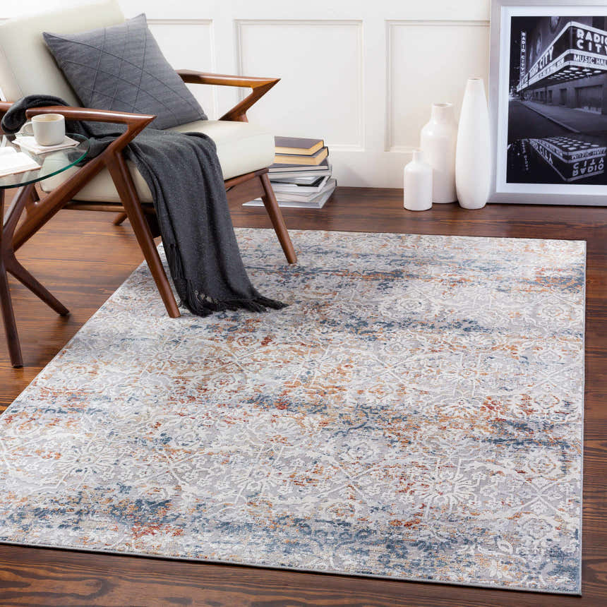Living room scene with a Marden Textured Luxe Area Rug in brick red, camel, charcoal, and gray under a modern chair. Roomscene-Rectangle